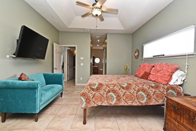 bedroom featuring a raised ceiling, tile patterned floors, and ceiling fan
