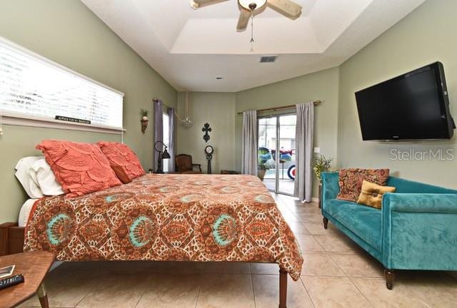 tiled bedroom with access to outside, a tray ceiling, and ceiling fan