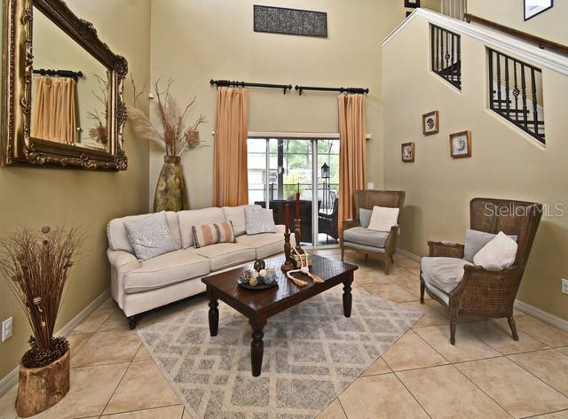 living area featuring light tile patterned floors, baseboards, and a towering ceiling