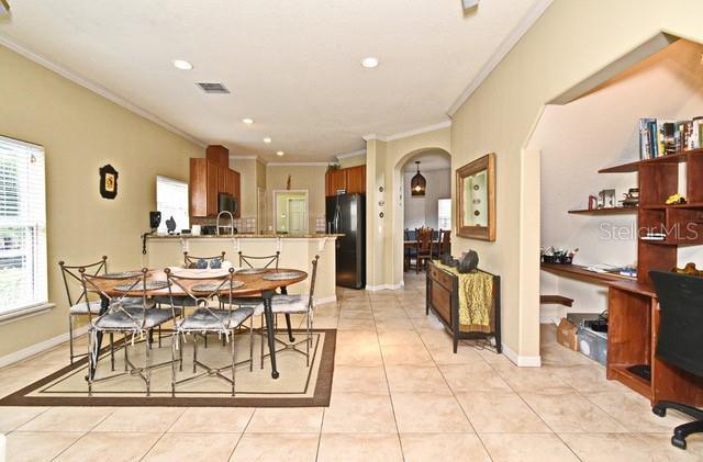 dining area featuring ornamental molding, healthy amount of natural light, arched walkways, light tile patterned floors, and recessed lighting