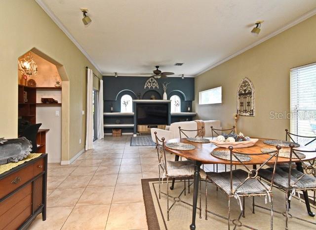 dining space featuring crown molding, a ceiling fan, arched walkways, and light tile patterned floors