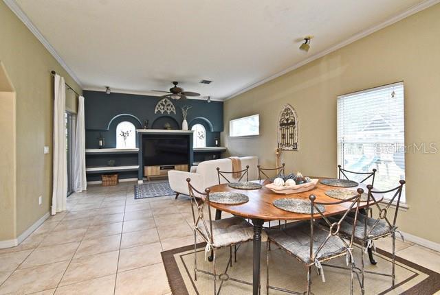 dining space featuring crown molding, a ceiling fan, light tile patterned floors, and baseboards