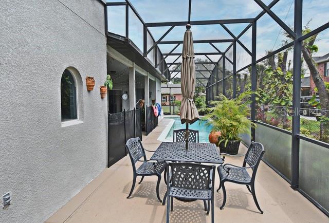 view of patio / terrace featuring glass enclosure and an outdoor pool