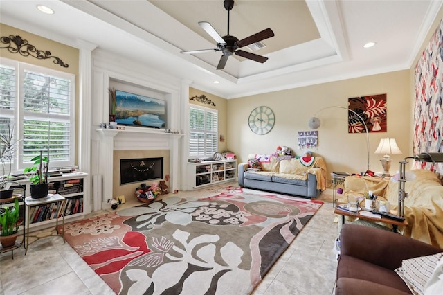 6686 SE 135th St, Summerfield, FL 34491 - tiled living room with a ceiling fan, a tray ceiling, a fireplace with flush hearth, recessed lighting, and crown molding