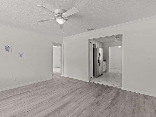 empty room with ceiling fan, a textured ceiling, light wood-style floors, ornamental molding, and baseboards