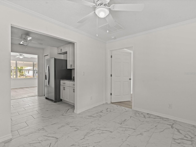 unfurnished room featuring a ceiling fan, light marble finish flooring, baseboards, and ornamental molding