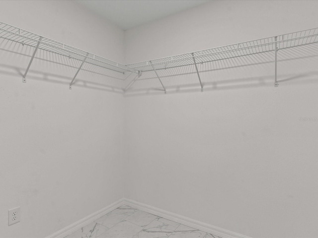 walk in closet featuring light marble finish floors