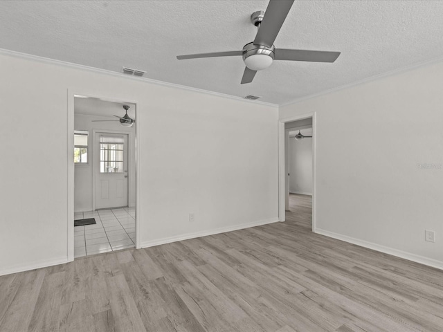 empty room featuring a ceiling fan, a textured ceiling, wood finished floors, ornamental molding, and baseboards