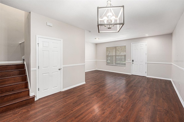 unfurnished dining area with stairs, a chandelier, dark wood-style floors, and baseboards
