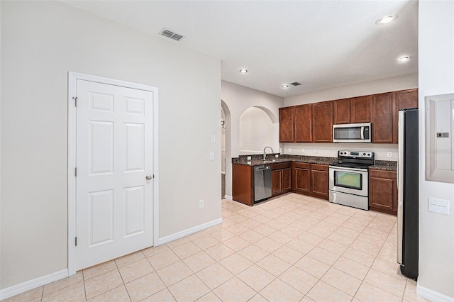 kitchen with stainless steel appliances, arched walkways, a sink, recessed lighting, and baseboards