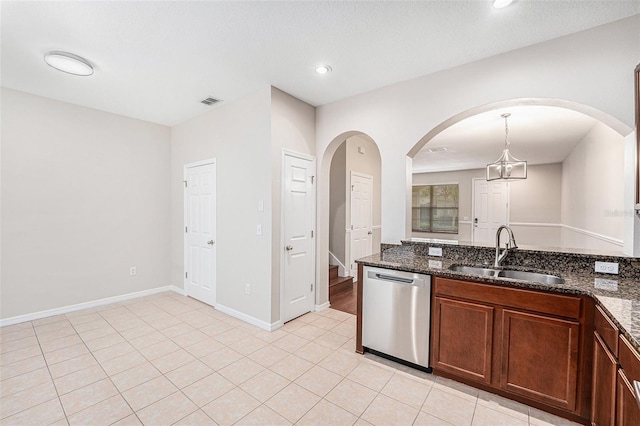 kitchen featuring dishwasher, a sink, arched walkways, dark stone counters, and decorative light fixtures