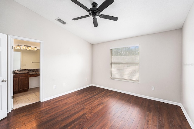 unfurnished bedroom with hardwood / wood-style floors, baseboards, lofted ceiling, ceiling fan, and connected bathroom