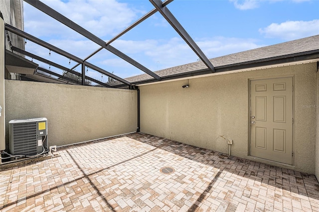 view of patio with central air condition unit and a lanai