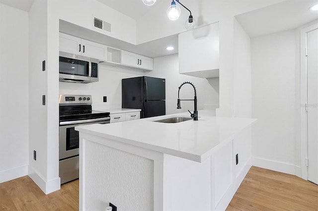 kitchen with stainless steel appliances, a sink, baseboards, light wood-style floors, and recessed lighting
