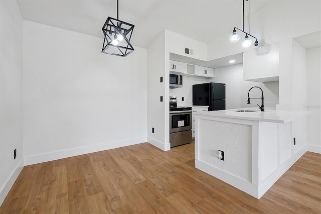 kitchen with appliances with stainless steel finishes, a sink, white cabinets, light wood finished floors, and light countertops