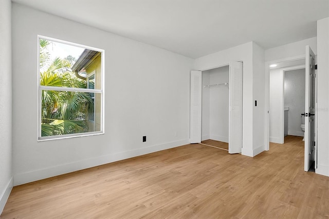 unfurnished bedroom featuring light wood-type flooring, baseboards, and a closet