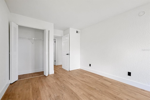 unfurnished bedroom with light wood-type flooring, a closet, and baseboards