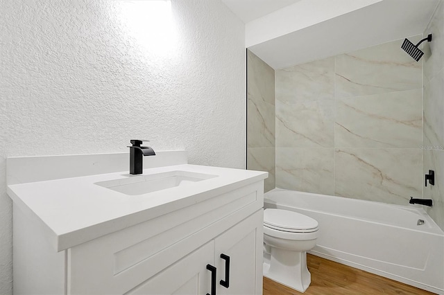 bathroom with wood finished floors, toilet, shower / tub combination, vanity, and a textured wall