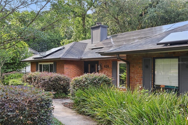 628 Riverpark Cir, Longwood, FL 32779 - view of home's exterior featuring brick siding, a shingled roof, solar panels, and a chimney