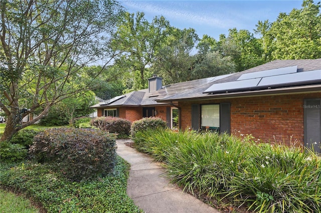 628 Riverpark Cir, Longwood, FL 32779 - view of property exterior featuring brick siding, solar panels, and a chimney