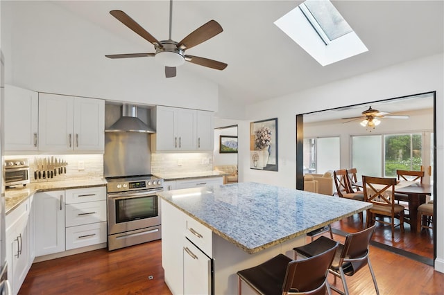 628 Riverpark Cir, Longwood, FL 32779 - kitchen featuring stainless steel electric range, wall chimney range hood, light stone countertops, a ceiling fan, and high vaulted ceiling