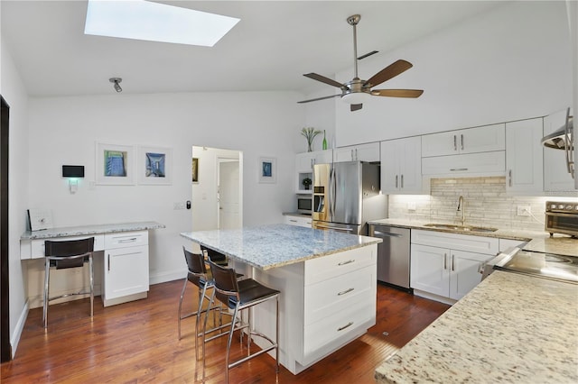 628 Riverpark Cir, Longwood, FL 32779 - kitchen featuring appliances with stainless steel finishes, a sink, backsplash, a kitchen island, and white cabinetry