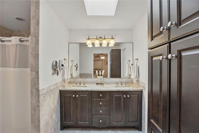 628 Riverpark Cir, Longwood, FL 32779 - bathroom with tile walls, double vanity, a tile shower, tile patterned flooring, and a wainscoted wall