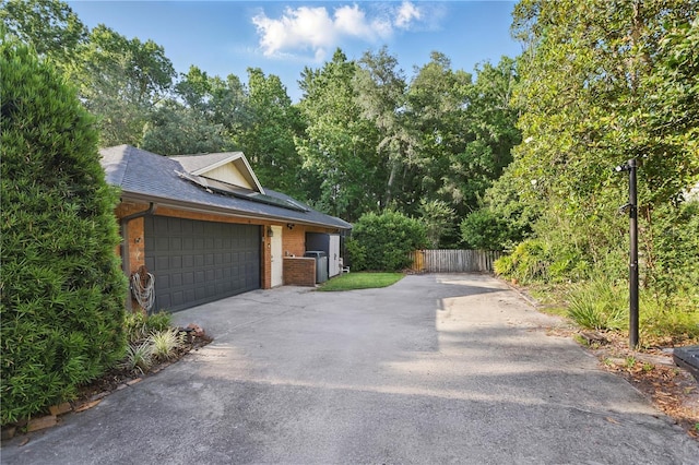 628 Riverpark Cir, Longwood, FL 32779 - view of side of property featuring asphalt driveway, roof with shingles, fence, brick siding, and an attached garage