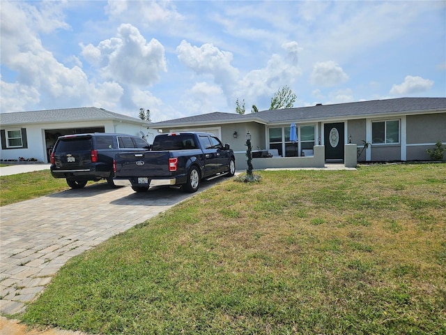 119 Caddy Rd, Rotonda West, FL 33947 - single story home with decorative driveway, an attached garage, stucco siding, and a front lawn