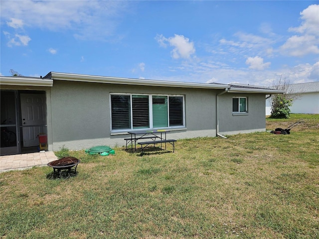 119 Caddy Rd, Rotonda West, FL 33947 - rear view of property featuring a fire pit, stucco siding, and a lawn