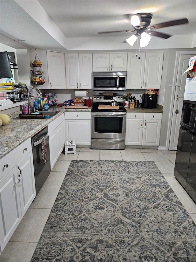 119 Caddy Rd, Rotonda West, FL 33947 - kitchen with appliances with stainless steel finishes, a sink, light tile patterned floors, a ceiling fan, and white cabinetry