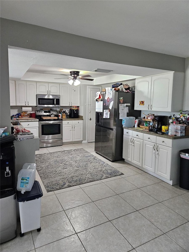 119 Caddy Rd, Rotonda West, FL 33947 - kitchen featuring appliances with stainless steel finishes, light tile patterned floors, ceiling fan, white cabinetry, and a raised ceiling