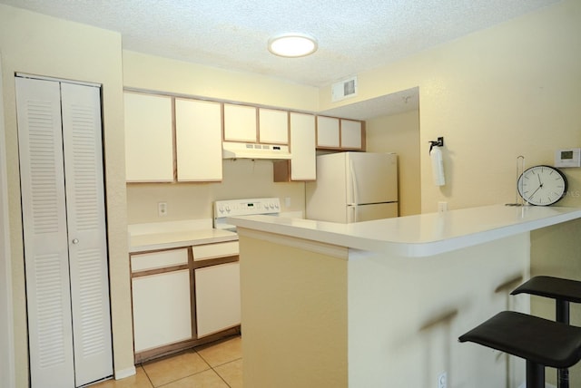 2208 Antigua Pl Unit 932, Kissimmee, FL 34741 - kitchen with freestanding refrigerator, under cabinet range hood, a peninsula, a breakfast bar, and light countertops