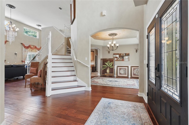 foyer featuring a chandelier, arched walkways, hardwood / wood-style flooring, stairway, and baseboards