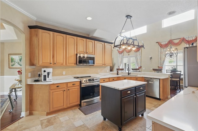 kitchen featuring stainless steel appliances, a sink, a chandelier, a peninsula, and crown molding