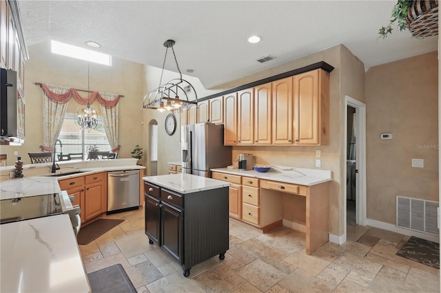 kitchen with stainless steel appliances, a sink, stone tile floors, a chandelier, and pendant lighting