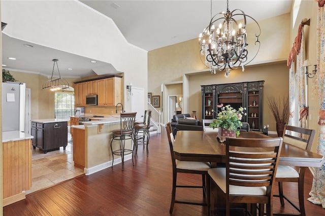 dining space with a high ceiling, hardwood / wood-style floors, and a chandelier