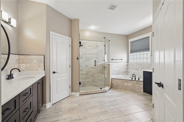 full bathroom featuring a stall shower, a garden tub, and vanity