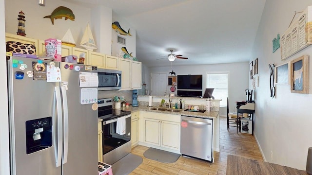 12381 Antonio Cir, Orlando, FL 32826 - kitchen featuring appliances with stainless steel finishes, a sink, a peninsula, a ceiling fan, and light wood-type flooring