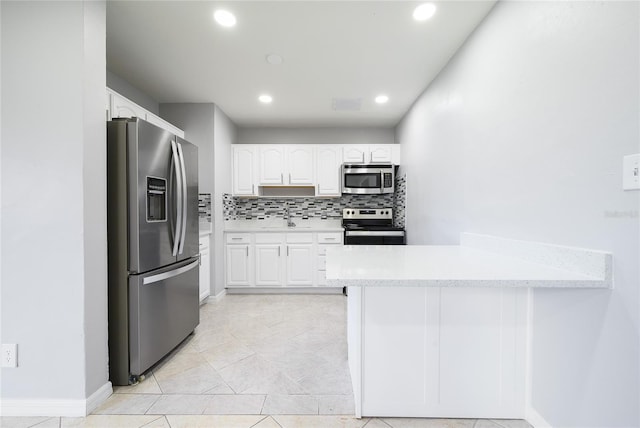 4824 Shoshone St, Orlando, FL 32819 - kitchen featuring appliances with stainless steel finishes, a peninsula, white cabinets, decorative backsplash, and light countertops