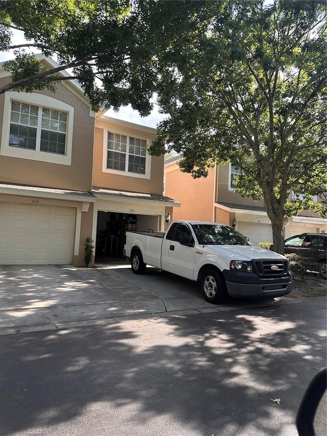 6450 Alcalde Ct Unit 106, Orlando, FL 32835 - view of property featuring stucco siding, a garage, and concrete driveway