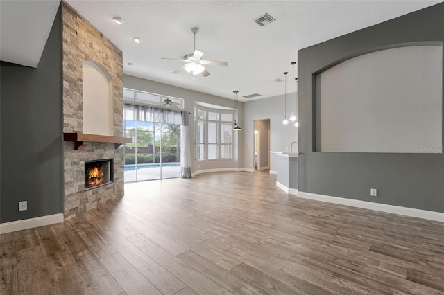 12411 Scarlett Sage Ct, Winter Garden, FL 34787 - unfurnished living room with a ceiling fan, wood finished floors, baseboards, and a stone fireplace