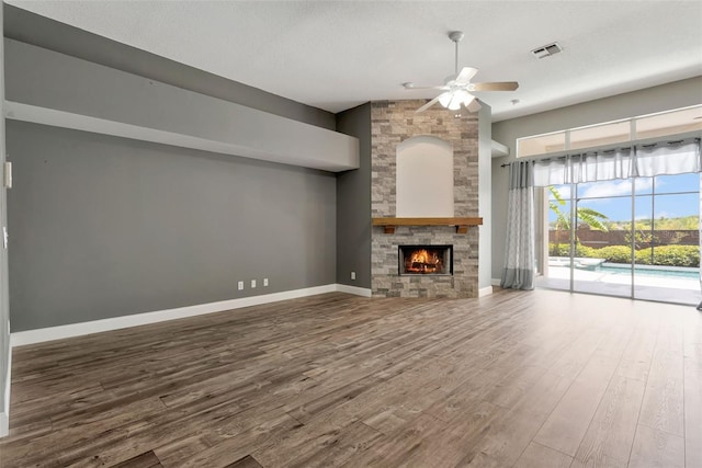 12411 Scarlett Sage Ct, Winter Garden, FL 34787 - unfurnished living room featuring ceiling fan, wood finished floors, a stone fireplace, baseboards, and a high ceiling