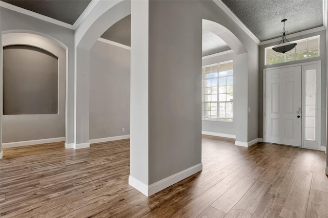 12411 Scarlett Sage Ct, Winter Garden, FL 34787 - entryway featuring ornamental molding, wood finished floors, arched walkways, baseboards, and a textured ceiling