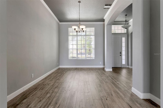 12411 Scarlett Sage Ct, Winter Garden, FL 34787 - entryway with a textured ceiling, wood finished floors, a chandelier, ornamental molding, and arched walkways