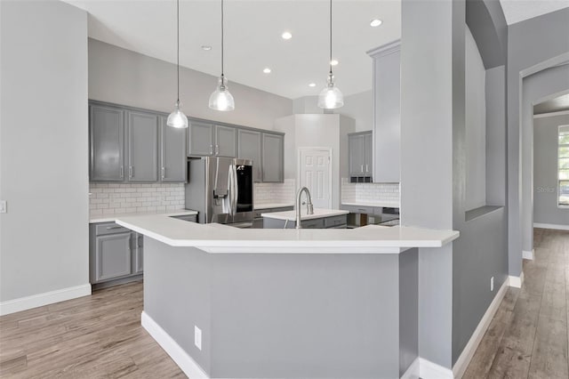 12411 Scarlett Sage Ct, Winter Garden, FL 34787 - kitchen with stainless steel fridge with ice dispenser, gray cabinetry, light wood-style flooring, backsplash, and recessed lighting