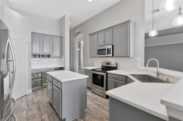12411 Scarlett Sage Ct, Winter Garden, FL 34787 - kitchen featuring appliances with stainless steel finishes, gray cabinets, a sink, arched walkways, and light wood-style flooring