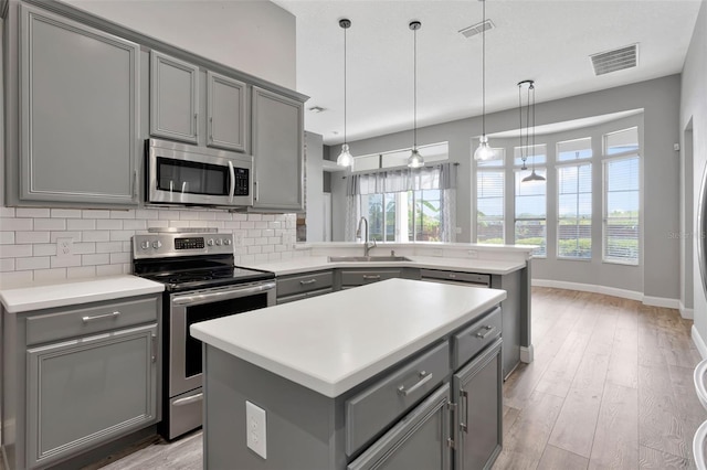 12411 Scarlett Sage Ct, Winter Garden, FL 34787 - kitchen with gray cabinets, stainless steel appliances, a sink, and tasteful backsplash