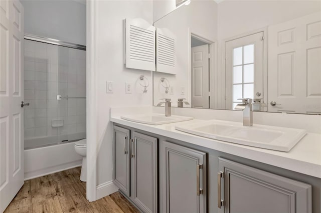 12411 Scarlett Sage Ct, Winter Garden, FL 34787 - bathroom featuring toilet, double vanity, wood finished floors, and enclosed tub / shower combo