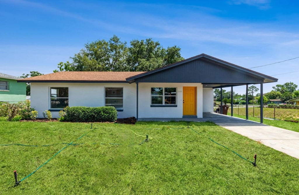 1105 Valencia Ave, Haines City, FL 33844 - ranch-style house with concrete driveway, an attached carport, stucco siding, and a front lawn